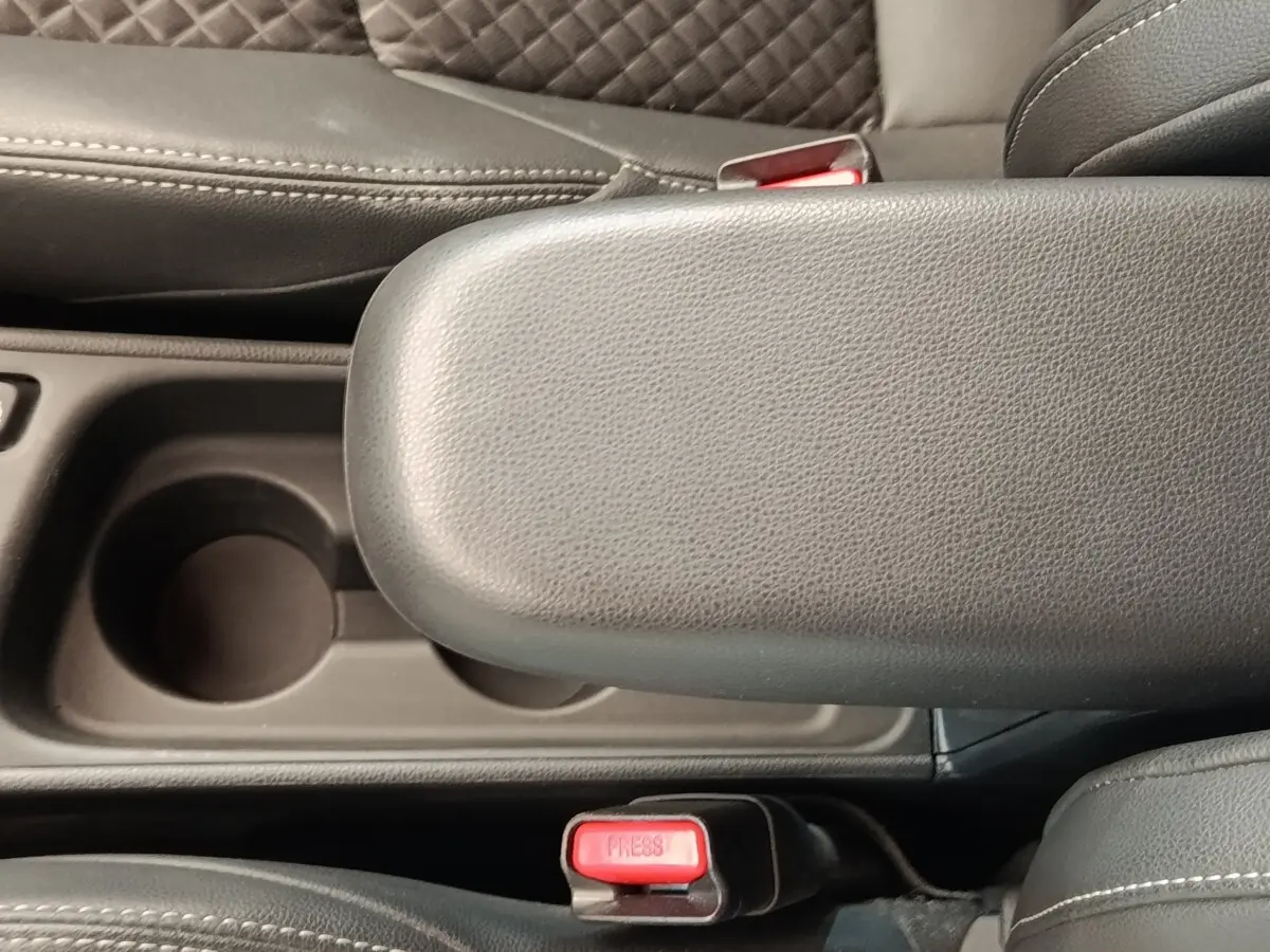 Gros plan sur l'accoudoir central noir et les ceintures de sécurité rouges de l'intérieur d'une Toyota Yaris Hybride 2022.