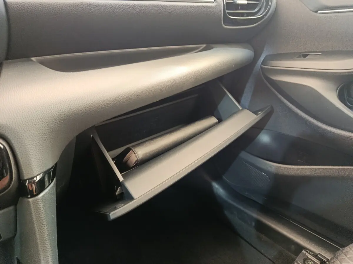 Vue intérieure côté passager de la boîte à gants ouverte de la Toyota Yaris Hybride 116h Collection 2022, finition noire.