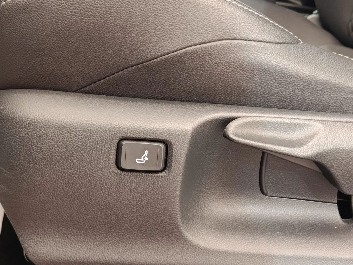 Détail du bouton de réglage lombaire sur le côté du siège avant en cuir gris foncé de la Toyota Yaris Hybride 116h Collection.