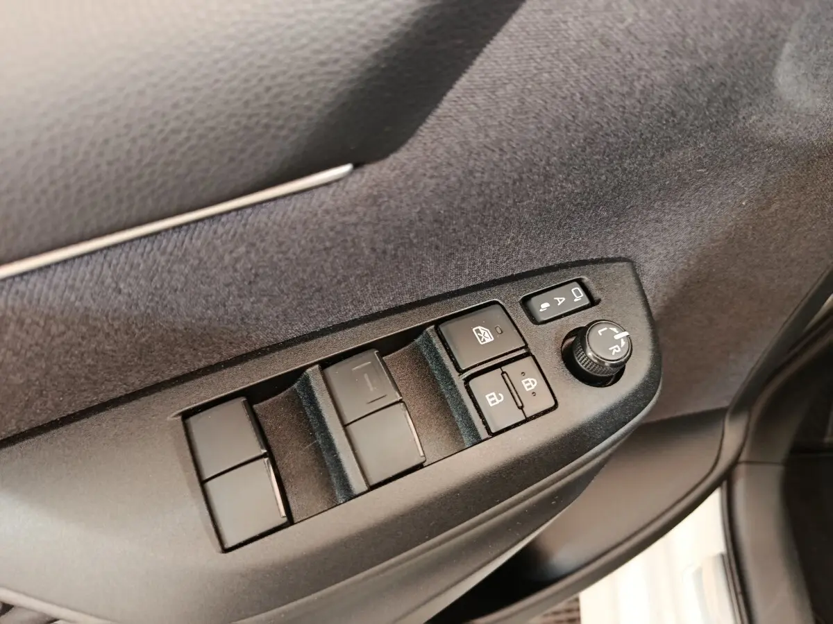 Détail des commandes de lève-vitres et réglage des rétroviseurs côté conducteur dans une Toyota Yaris Hybride blanche 2022.