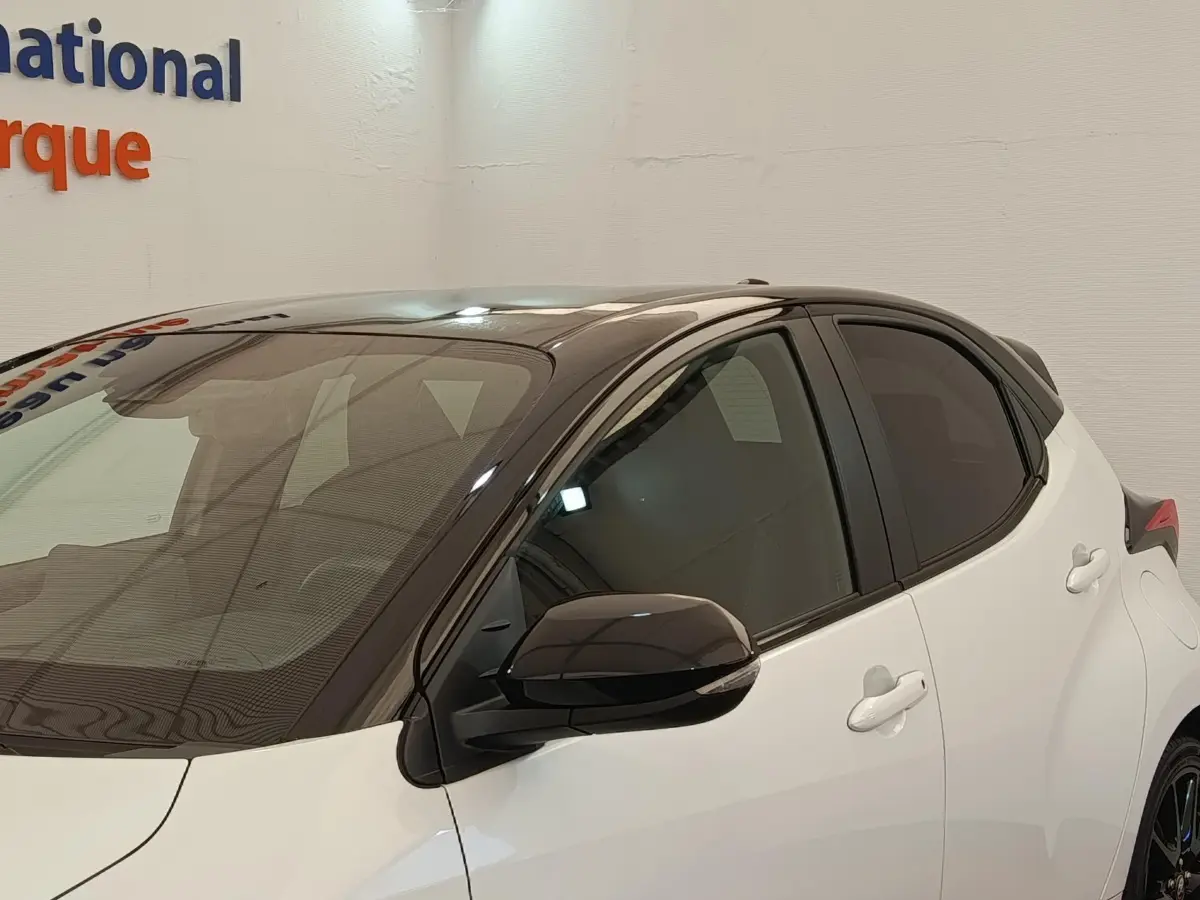 Vue de profil avant droit d'une Toyota Yaris Hybride 116h Collection blanche avec toit noir et rétroviseur noir.