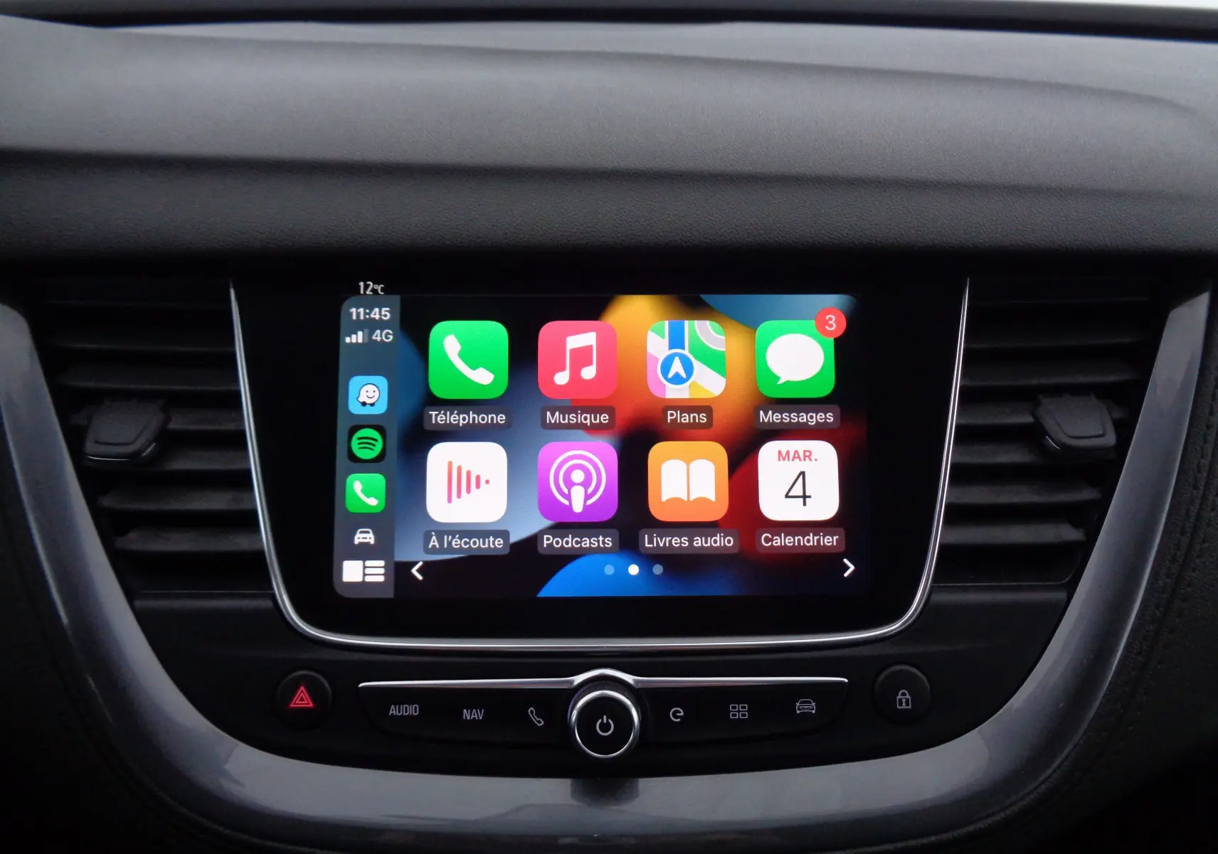 Écran tactile central allumé de l’Opel Grandland X blanc perle, vue frontale du tableau de bord avec commandes intégrées.