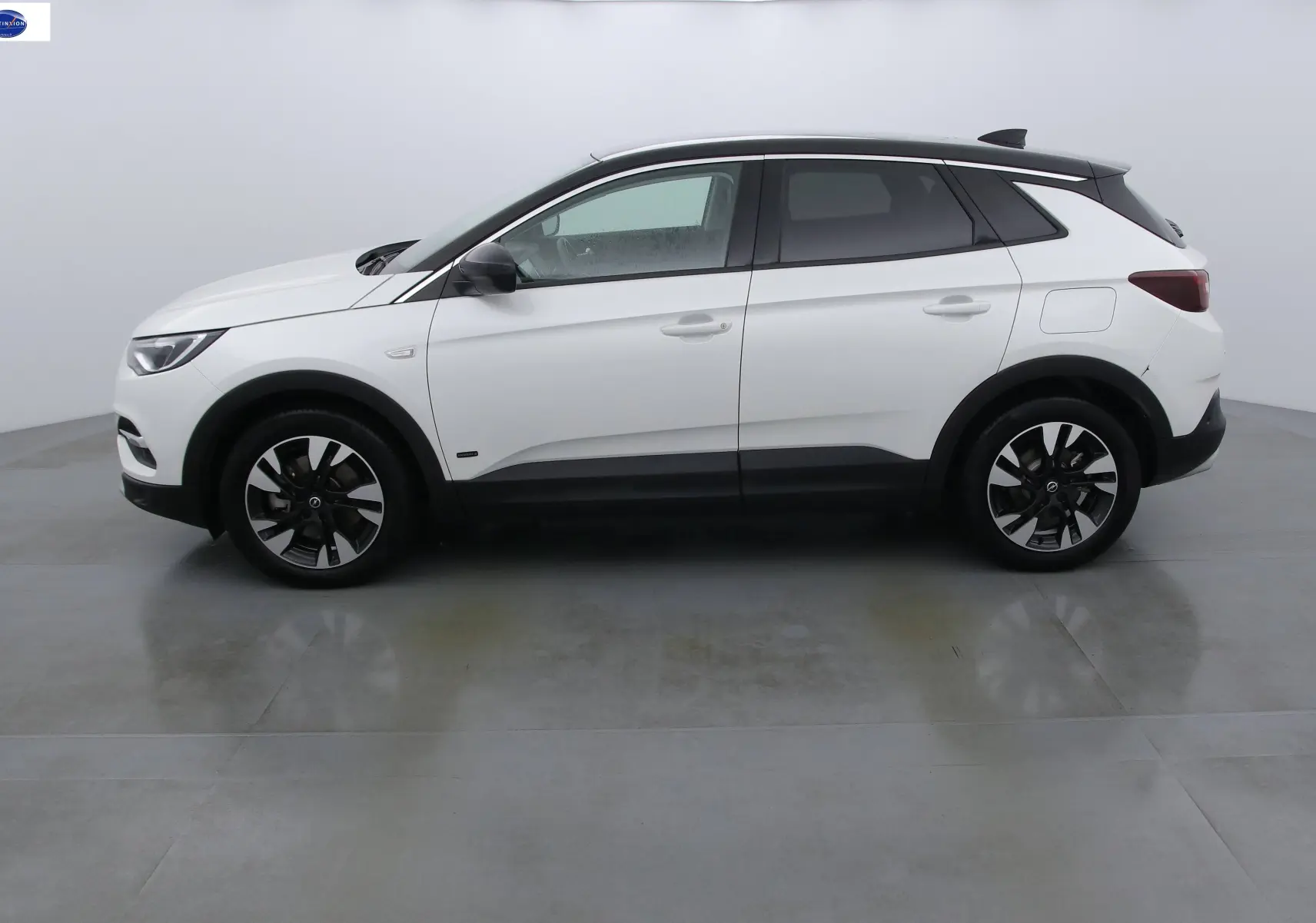 Profil côté gauche d'un Opel Grandland X blanc perle métal avec toit noir et jantes bicolores.