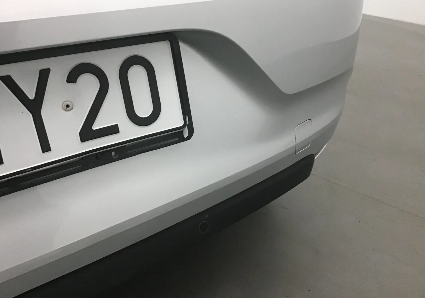 Gros plan sur le pare-chocs arrière gris platine d'une Renault Clio V 1.0 TCE 90 Zen avec plaque d'immatriculation partielle visible.