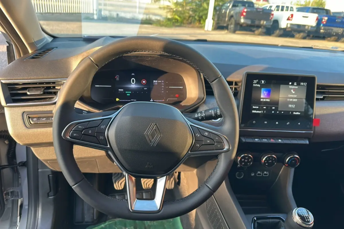 Vue intérieure centrée sur le volant Renault d'une Clio 2025, avec tableau de bord numérique et écran tactile.