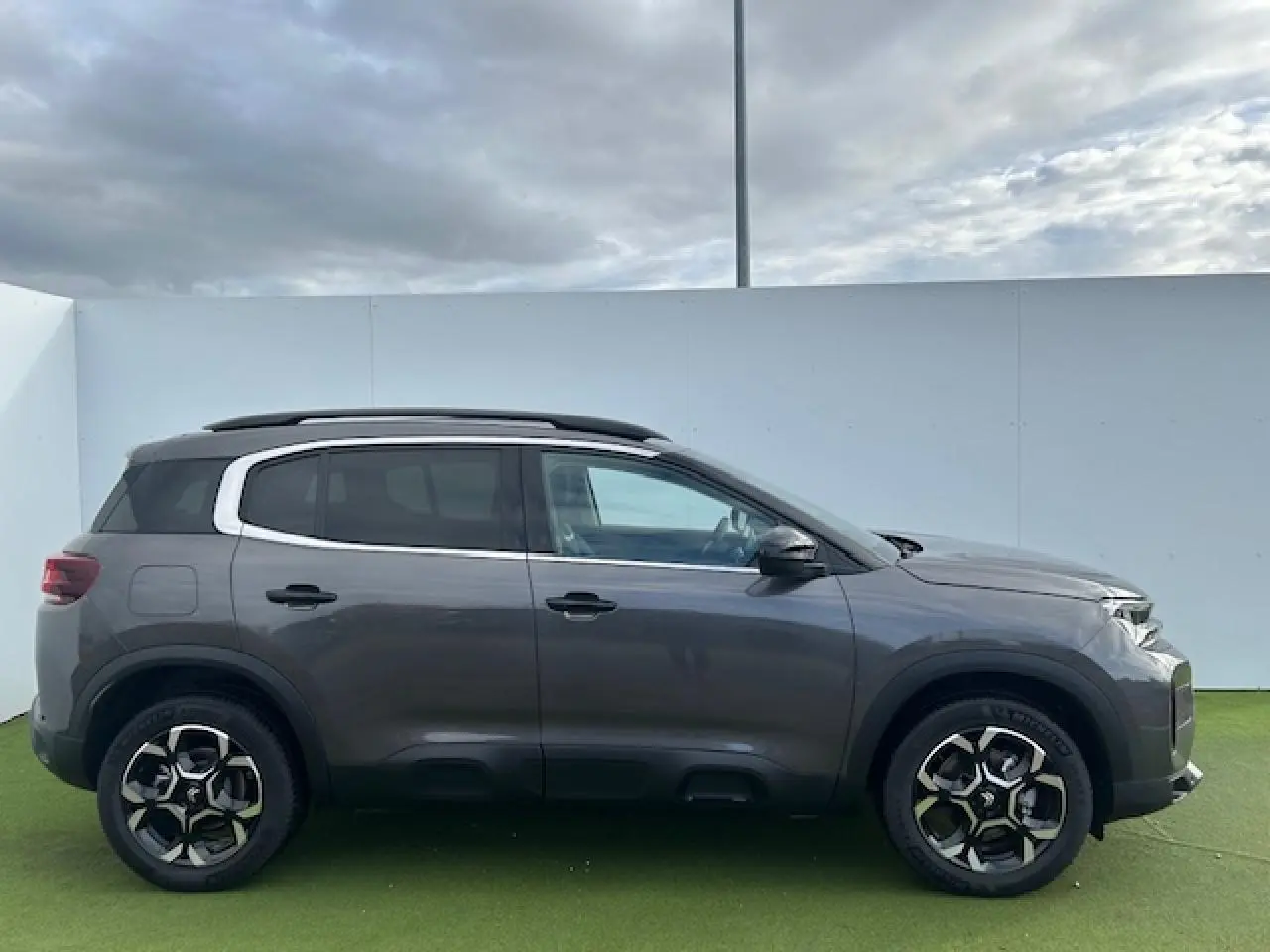 Profil droit du Citroën C5 Aircross gris platinium métallisé avec jantes alliage bi-ton et barres de toit noires.