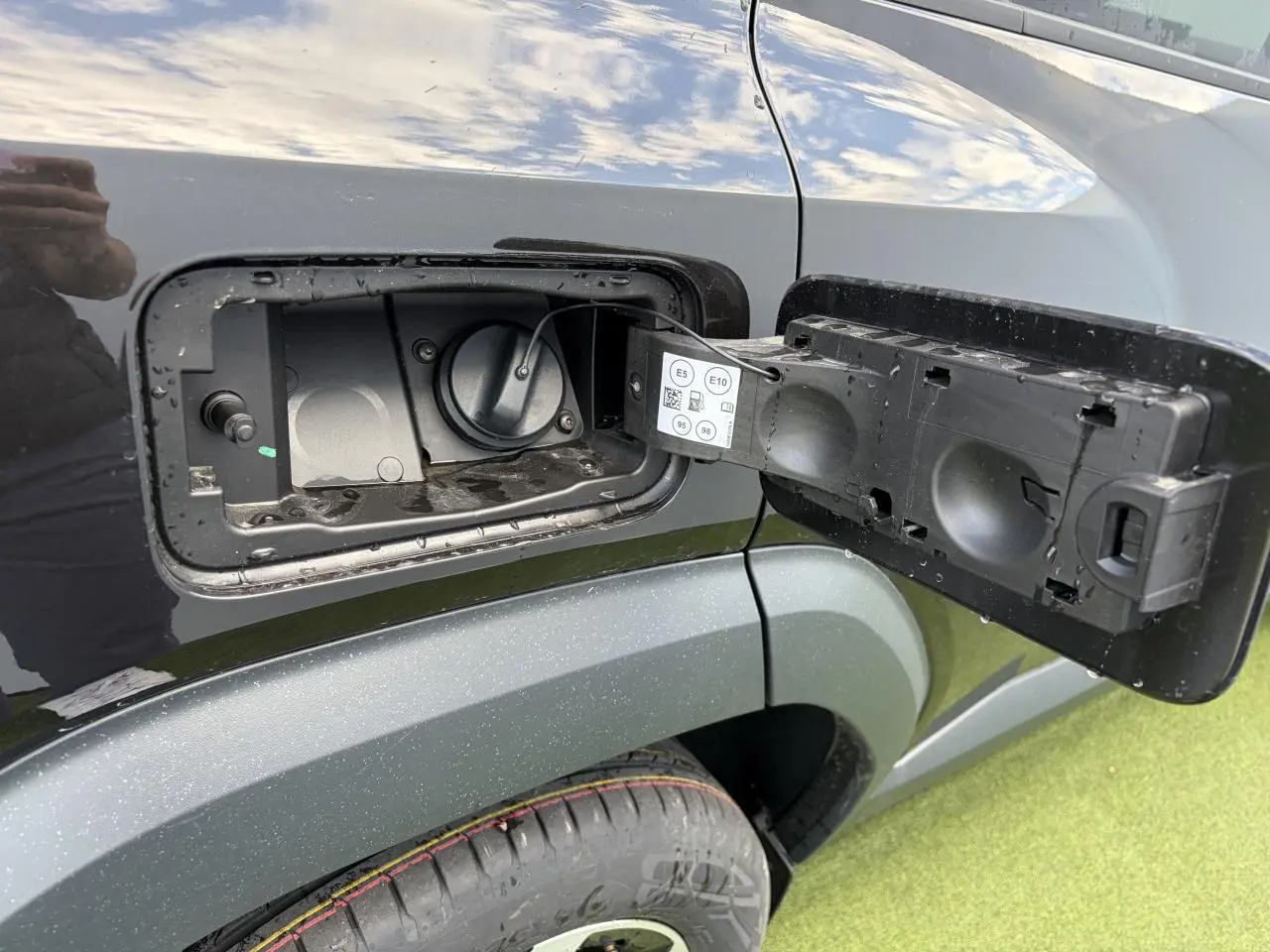 Bouchon de réservoir essence ouvert côté gauche sur DACIA BIGSTER noir nacré, vue rapprochée sur la trappe et la roue arrière.