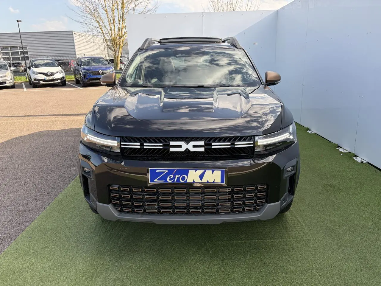 Vue avant d'un Dacia Bigster noir nacré avec calandre brun cuivré et toit panoramique ouvrant.