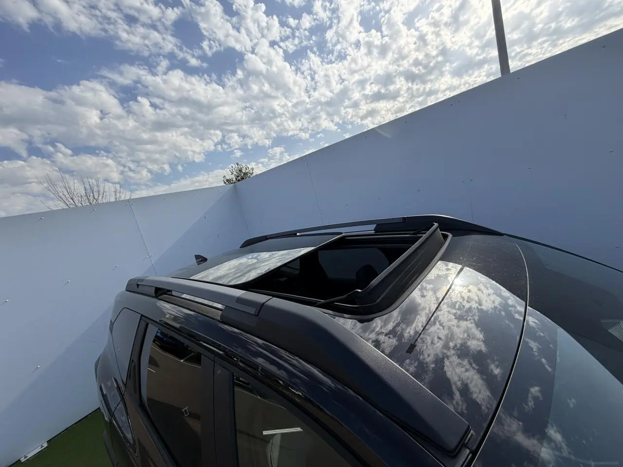 Toit ouvrant panoramique ouvert vu en plongée sur le côté gauche du Dacia Bigster noir nacré 2026.