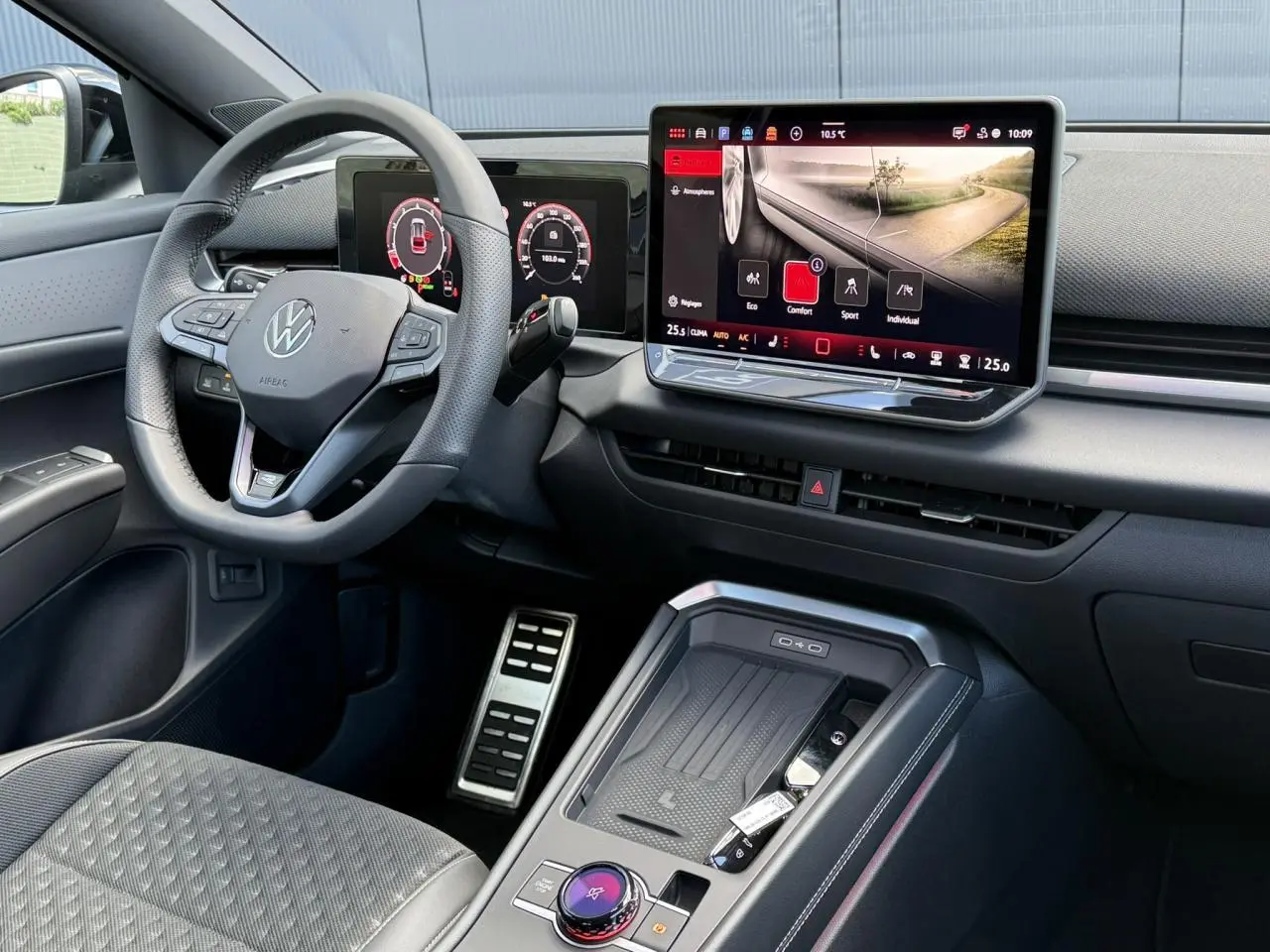 Vue intérieure côté conducteur du Volkswagen T-Roc 2026 noir, avec volant multifonction, écran tactile et pédalier acier.