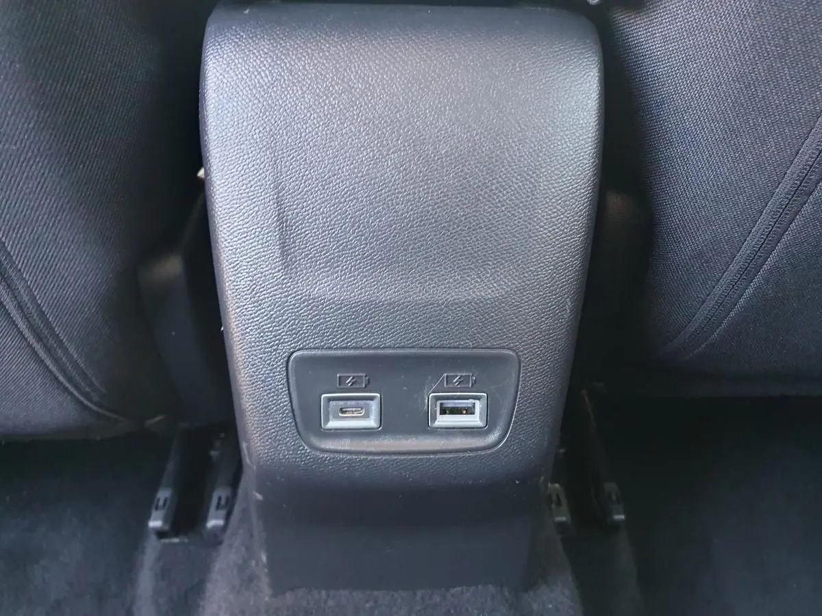 Prise USB type C et USB classique sur la console arrière d’une Peugeot 208 gris Artense, vue rapprochée intérieure.