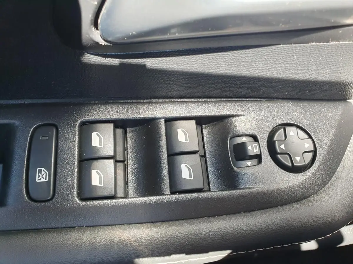 Commande des vitres électriques et réglage des rétroviseurs sur la porte côté conducteur d'une Peugeot 208 gris Artense.