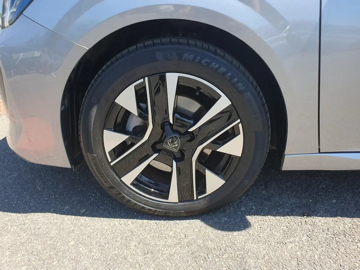 Gros plan sur la roue avant droite d’une Peugeot 208 gris Artense avec jante alliage bi-ton diamantée.