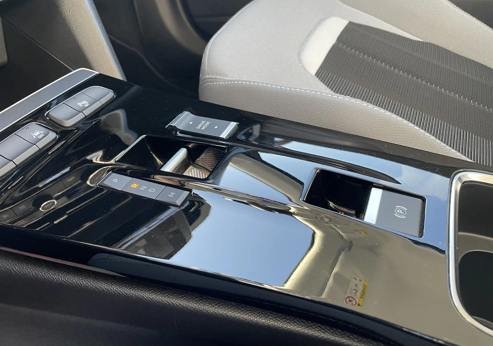 Gros plan sur la console centrale noire brillante de l’Opel Mokka 2023 avec levier de vitesse automatique et siège tissu gris.