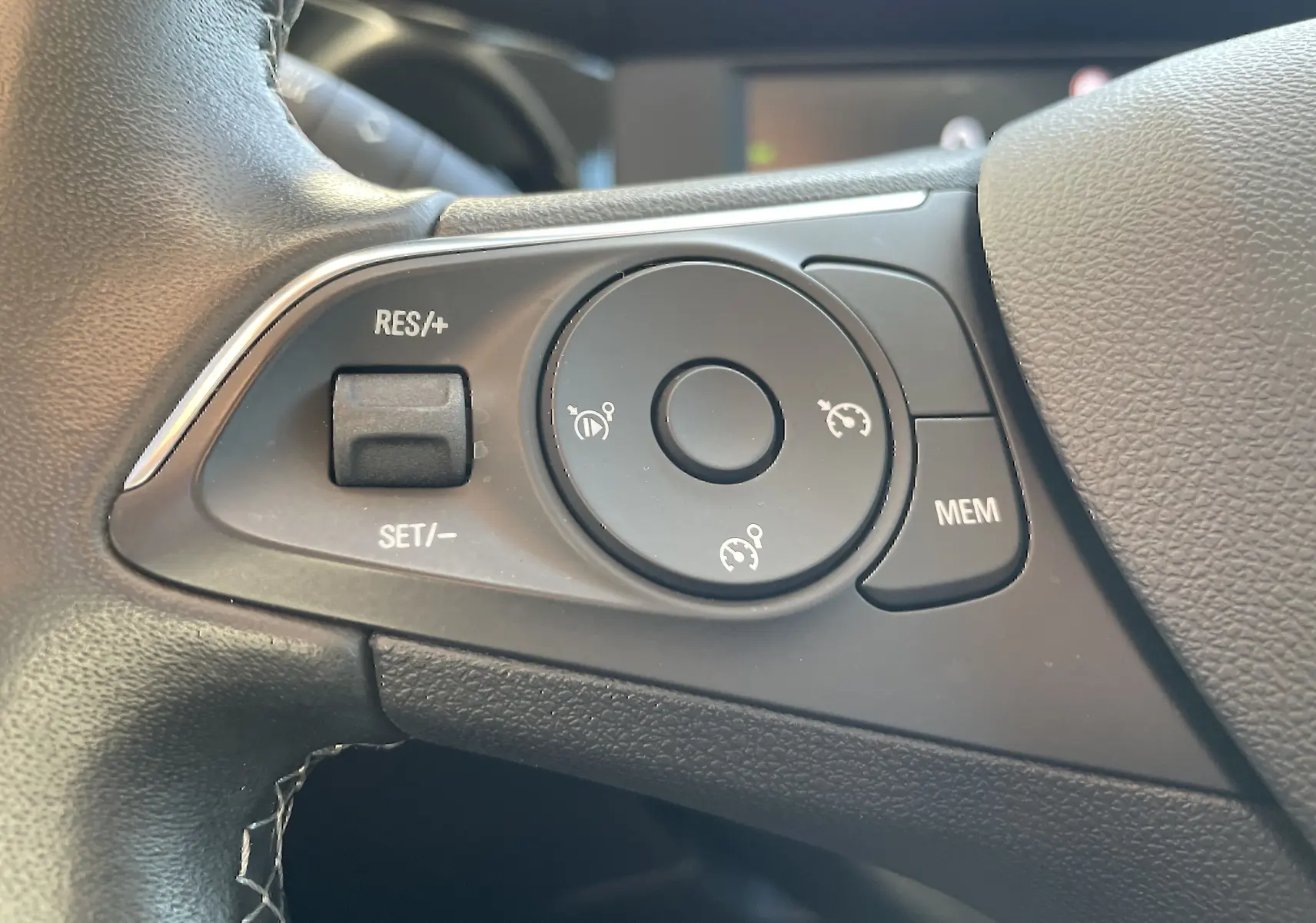Gros plan sur les commandes de régulateur de vitesse au volant d'un Opel Mokka 2023, intérieur gris noir.