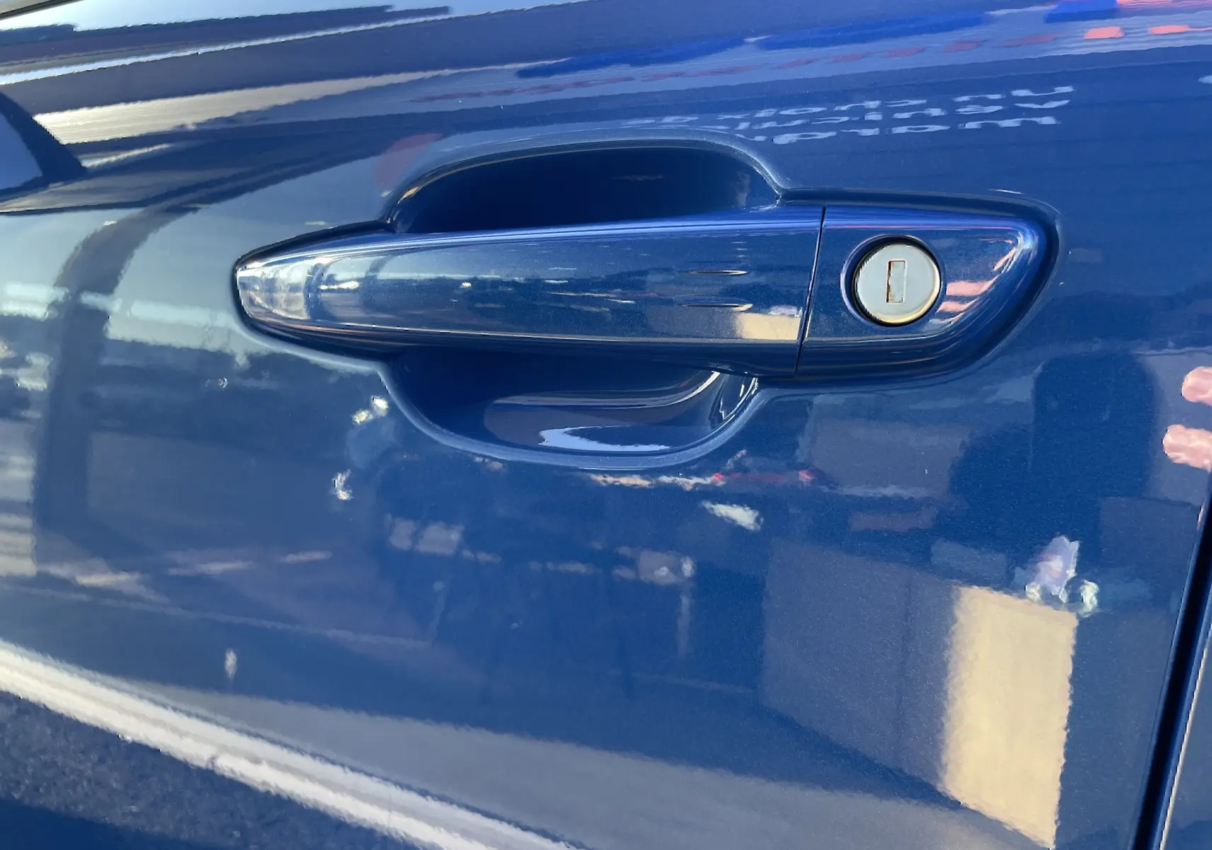 Gros plan sur la poignée de porte côté gauche de l’Opel Mokka 2023 en bleu Voltak avec serrure intégrée.