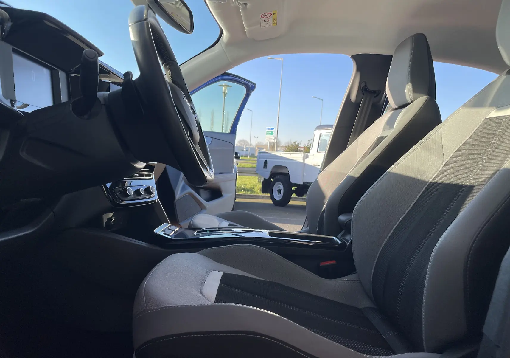 Vue intérieure côté conducteur de l’Opel Mokka 2023, sièges gris/noir et tableau de bord moderne avec volant multifonction.