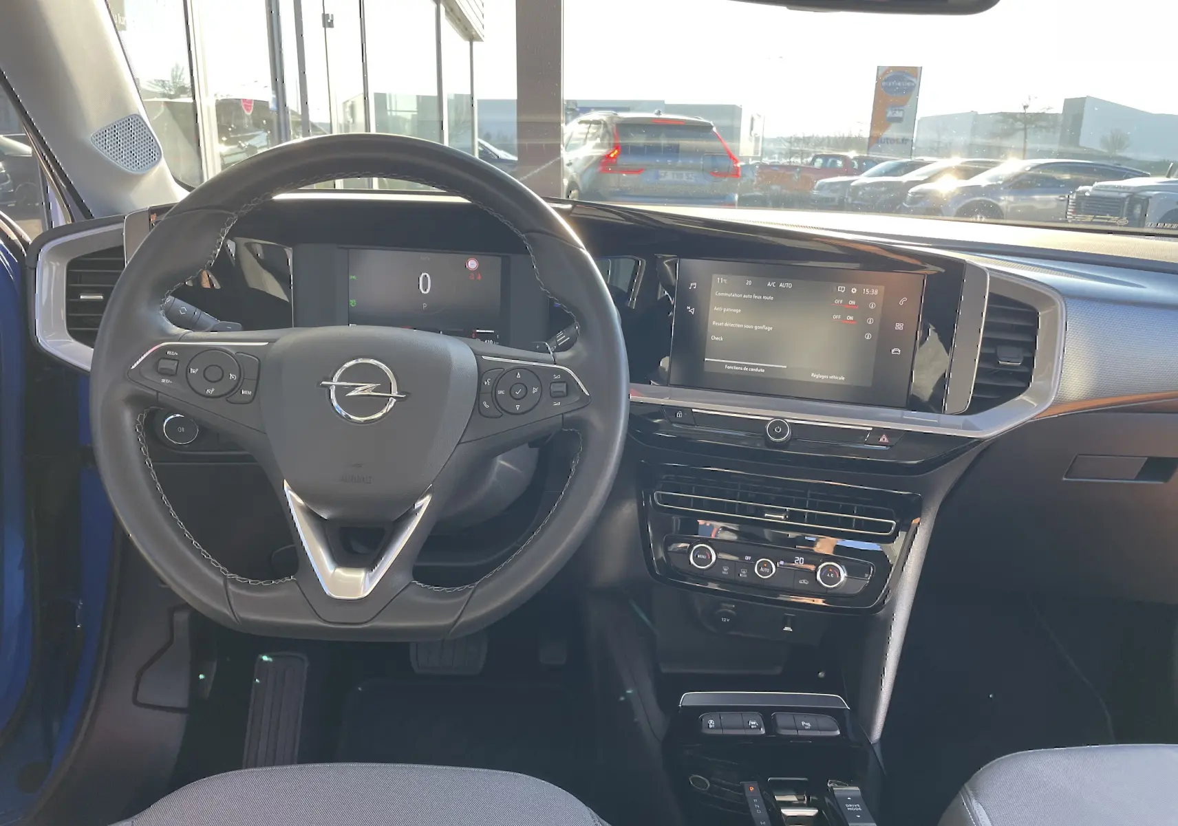 Vue intérieure centrée sur le volant et le tableau de bord de l’Opel Mokka bleu Voltak avec écran tactile et commandes au volant.