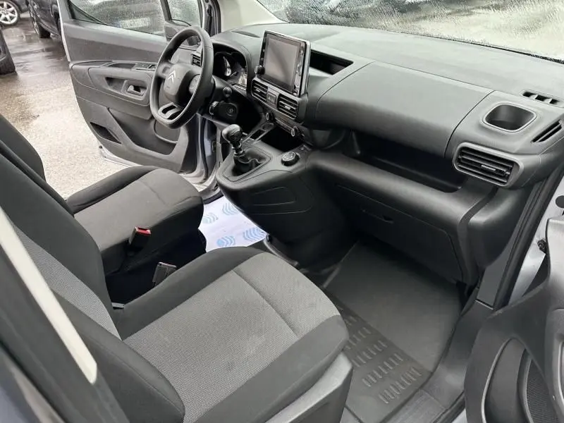Intérieur du Citroën Berlingo van gris métal 2020, vue côté conducteur montrant tableau de bord et sièges tissu noir.