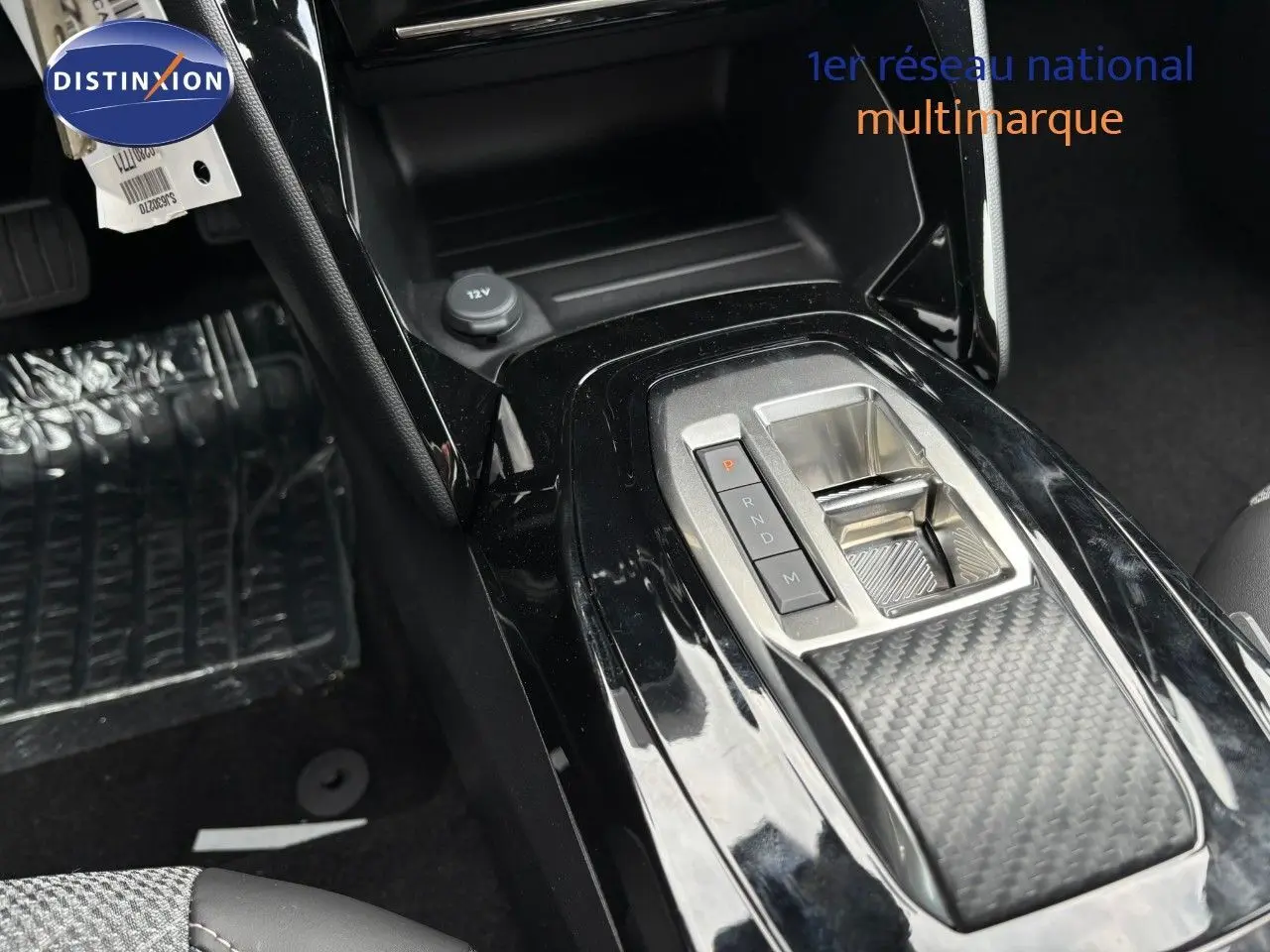 Gros plan sur la console centrale noire brillante du Peugeot 2008 Hybrid 2025 avec levier de vitesses électronique.