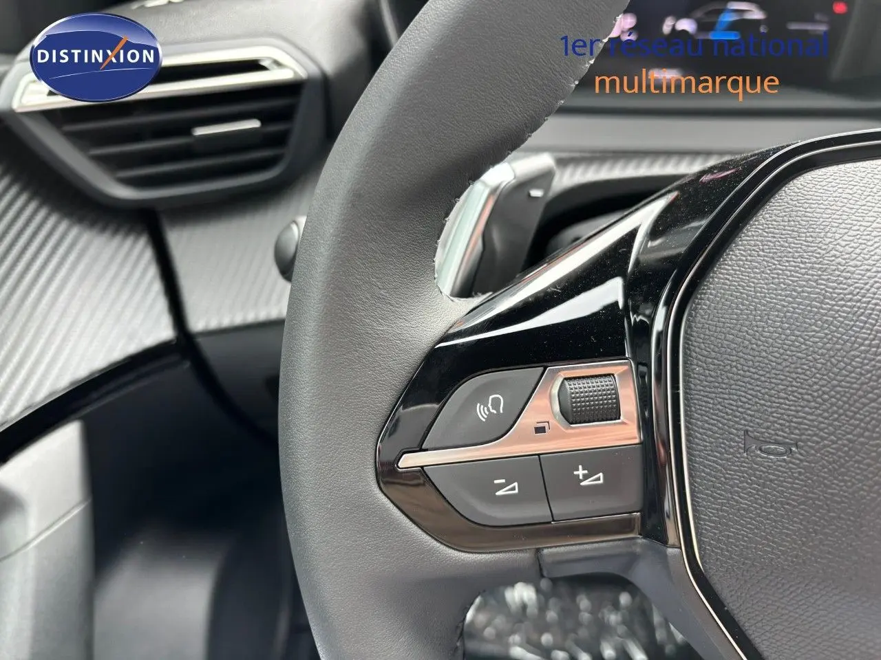 Gros plan sur le volant cuir noir du Peugeot 2008 Hybrid 136ch Allure, mettant en valeur les commandes intégrées côté gauche.