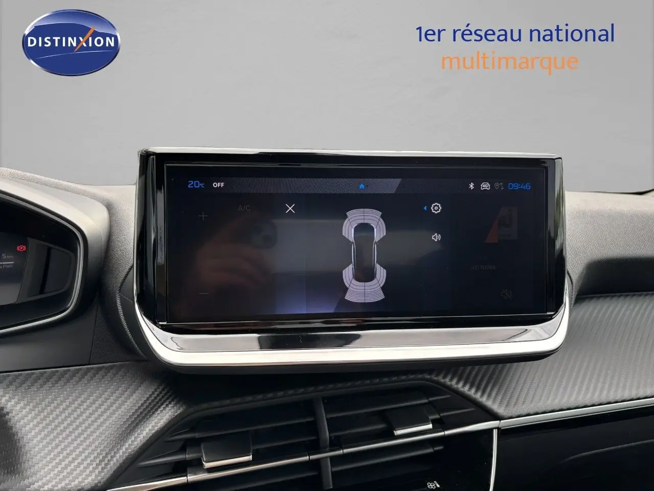 Écran tactile central du tableau de bord du Peugeot 2008 Hybrid 136ch Allure avec finition carbone et affichage de capteurs de proximité.