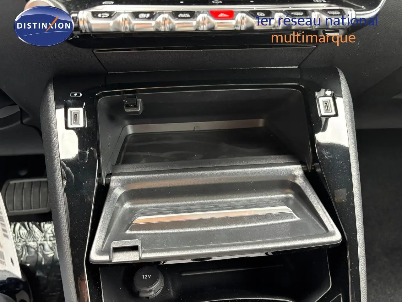 Vue rapprochée de la console centrale du Peugeot 2008 Hybrid 136ch Allure 2025, avec compartiment ouvert et prises USB visibles.