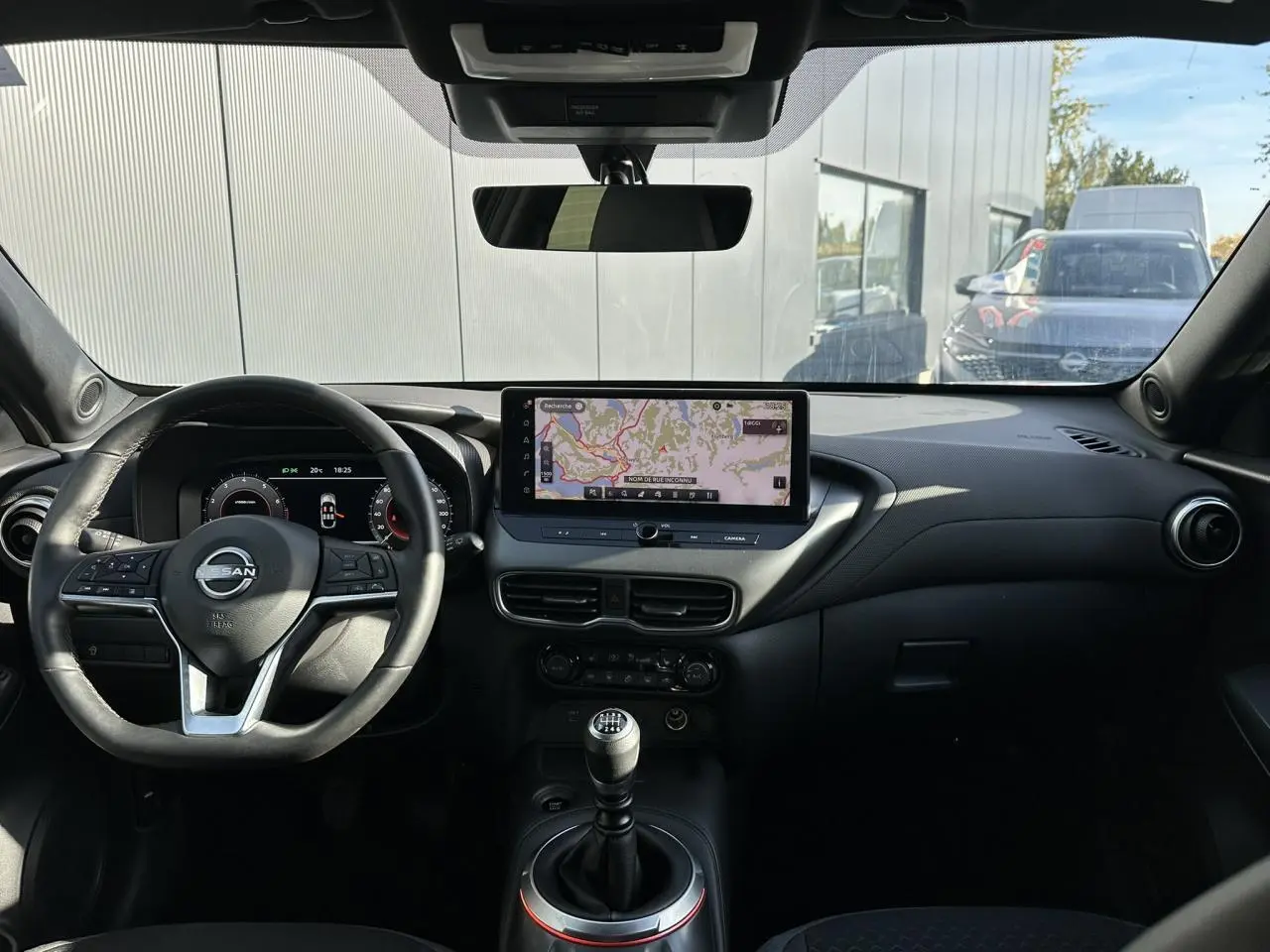 Intérieur noir du Nissan Juke 2025 vu de face, avec tableau de bord digital et écran tactile central affichant la navigation.