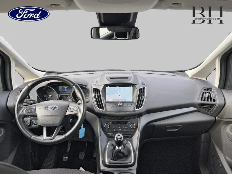 Vue intérieure avant du Ford C-MAX gris lunaire 2018, avec tableau de bord, volant cuir multifonction et écran tactile GPS.