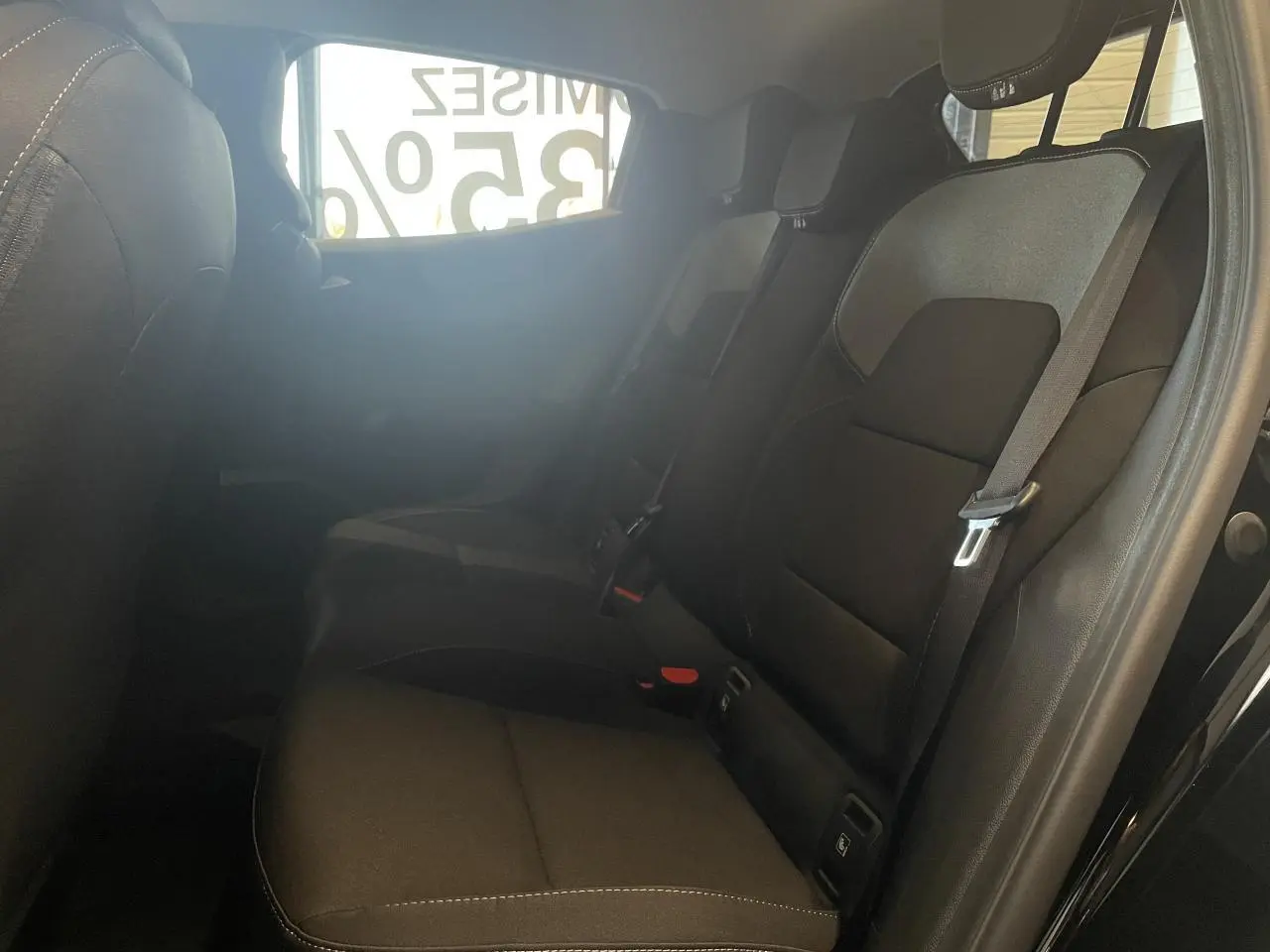 Vue intérieure côté droit des sièges arrière noirs de la Renault Clio 1.5 Blue dCi 2025 avec ceintures de sécurité visibles.