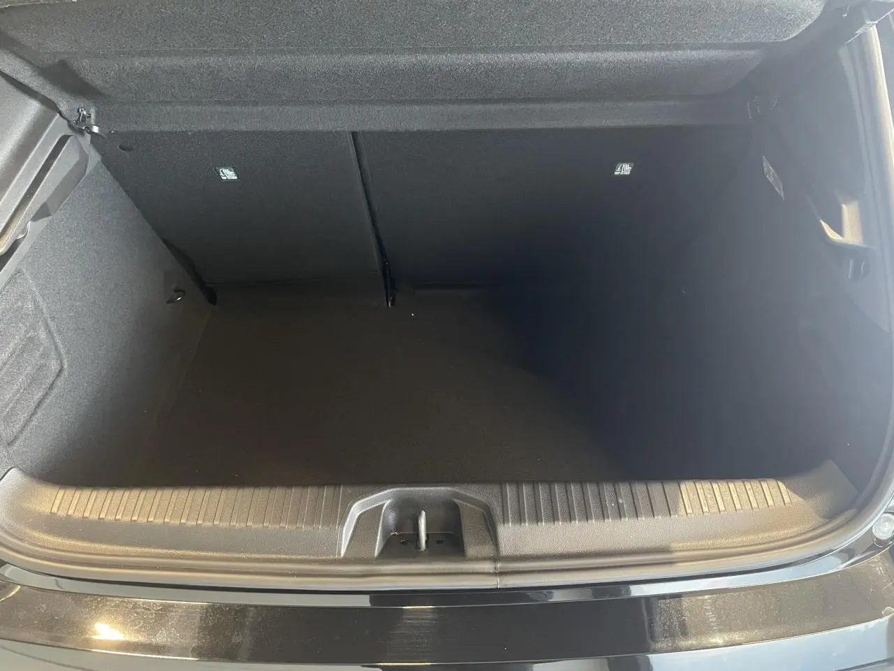 Coffre ouvert vu de face d'une Renault Clio 1.5 Blue dCi 2025 noir étoilé avec seuil de chargement visible.