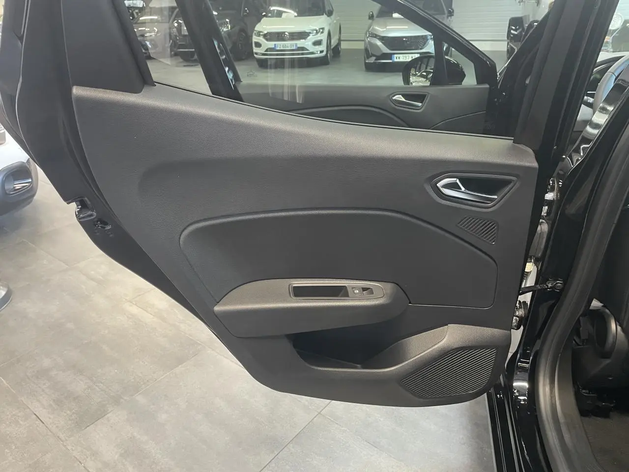 Porte arrière gauche ouverte de Renault Clio noire étoile, montrant la garniture intérieure sobre avec commande de vitre.