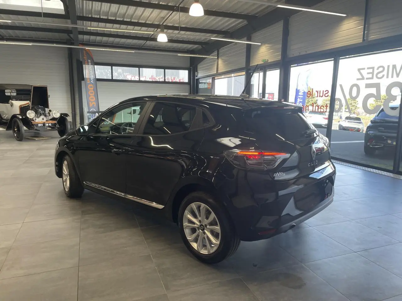 Renault Clio 2025 noir étoilé vue 3/4 arrière droit en intérieur avec jantes alu et feux LED allumés.