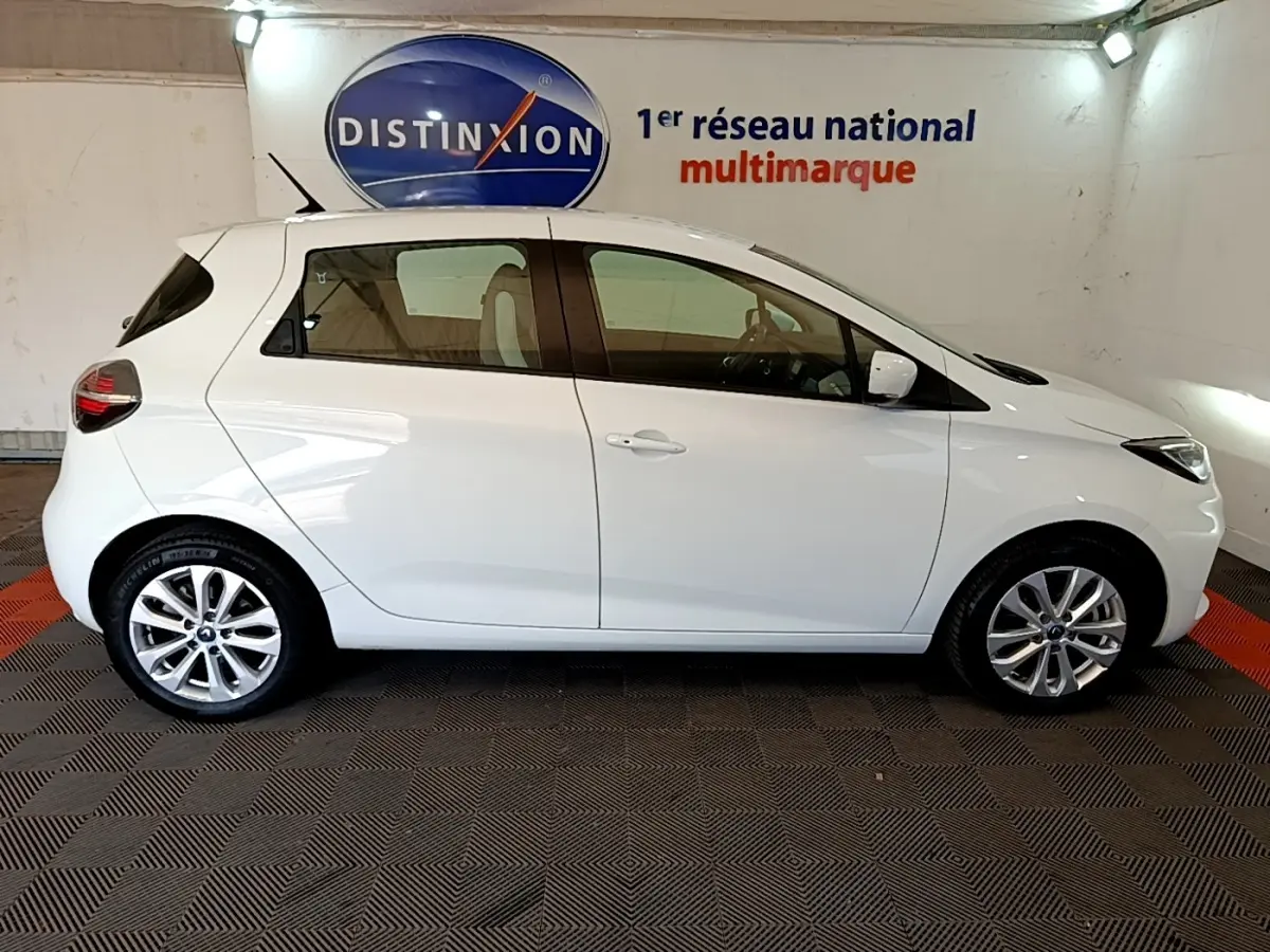 Profil latéral droit d'une Renault ZOE Zen R110 blanche de 2019, compacte et électrique, dans un showroom intérieur.