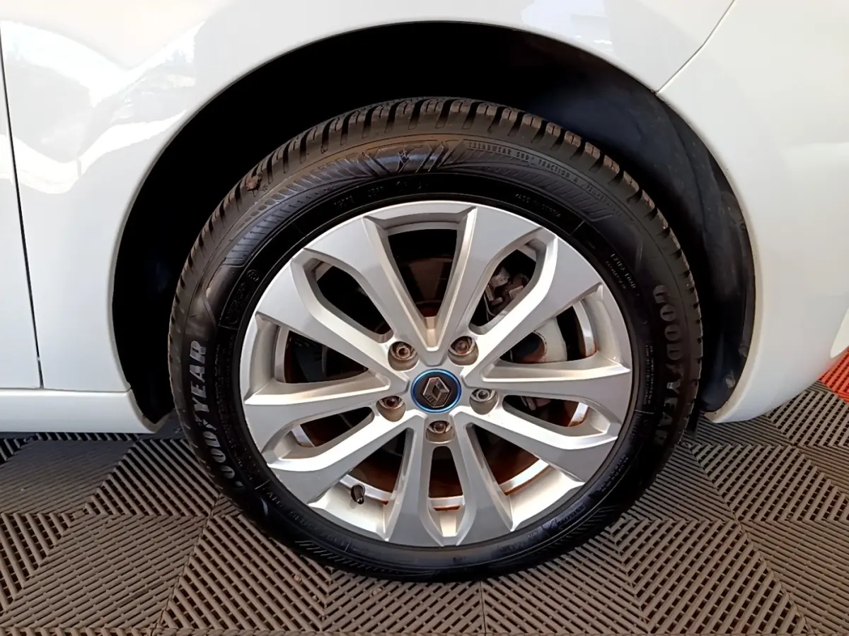 Gros plan sur la roue avant droite d'une Renault ZOE blanche, jante alliage argent avec logo Renault au centre.