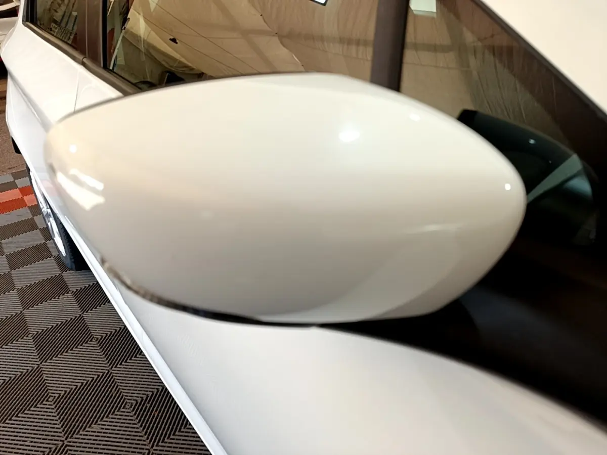 Gros plan sur le rétroviseur droit blanc d'une Renault ZOE Zen R110, avec la portière et vitre arrière visibles.