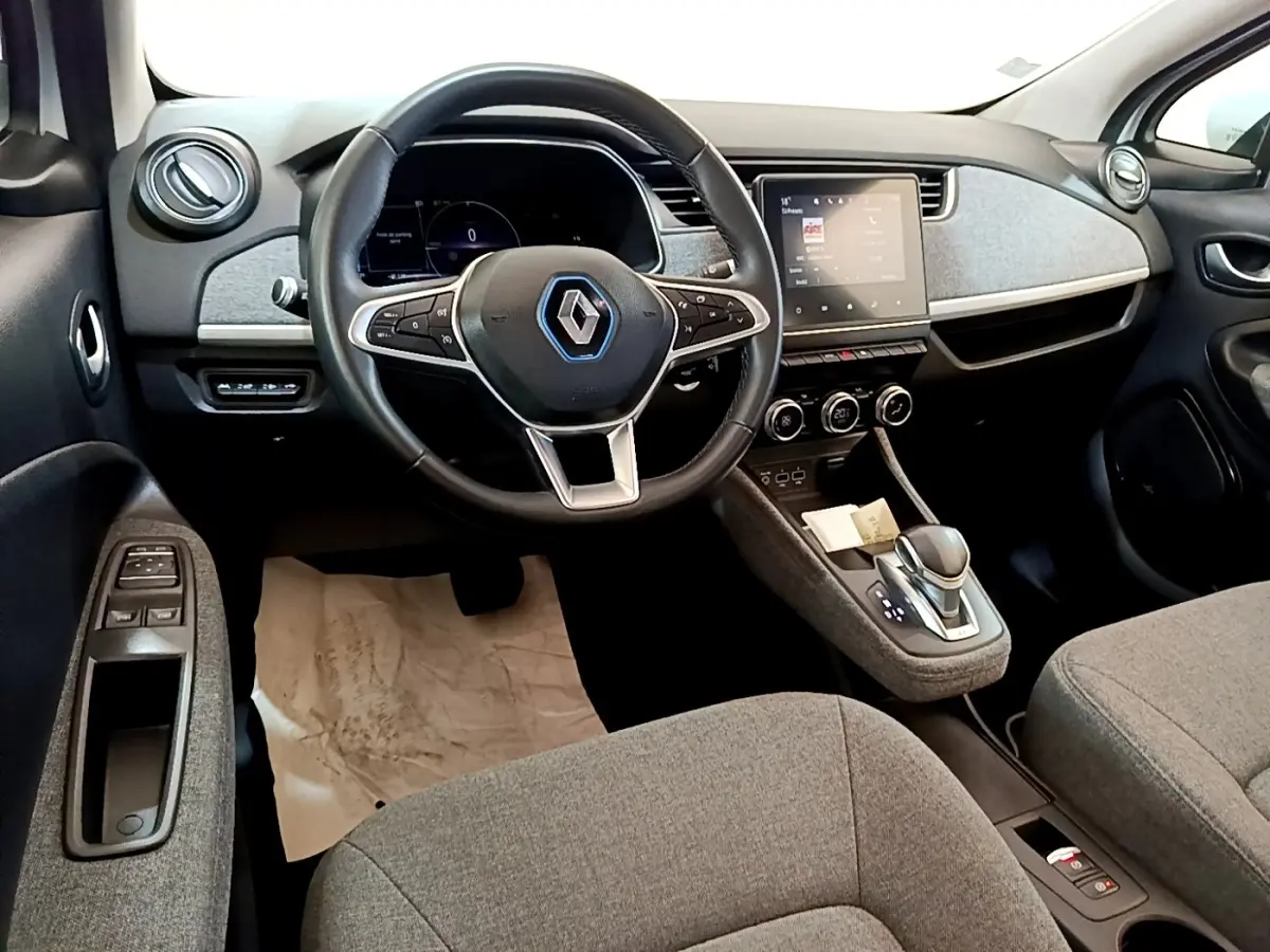 Vue intérieure avant de la Renault ZOE Zen R110, tableau de bord avec écran tactile et volant multifonctions en cuir synthétique.