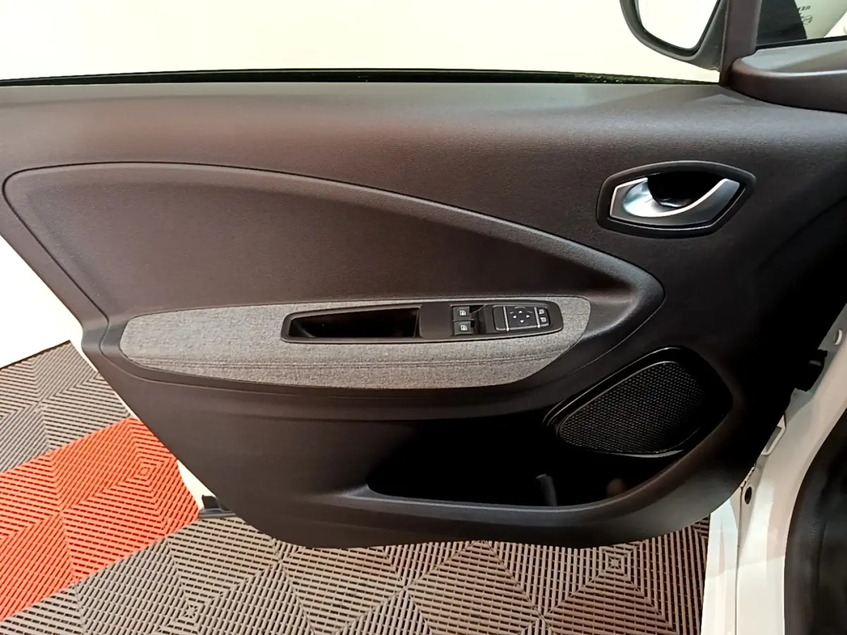 Vue intérieure de la porte avant gauche de la Renault ZOE blanche, avec panneau noir et insert tissu gris.