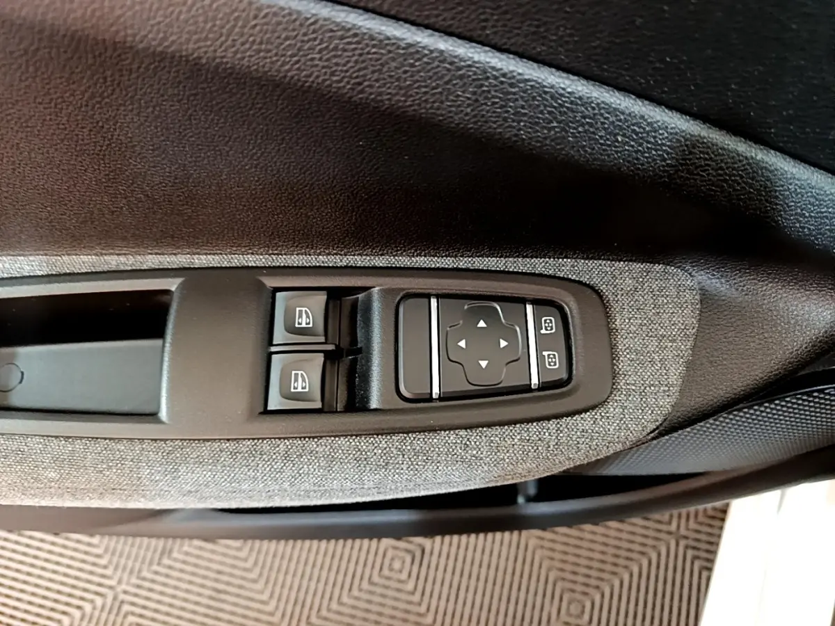 Détail des commandes des vitres et rétroviseurs sur la porte intérieure côté conducteur d’une Renault ZOE blanche.