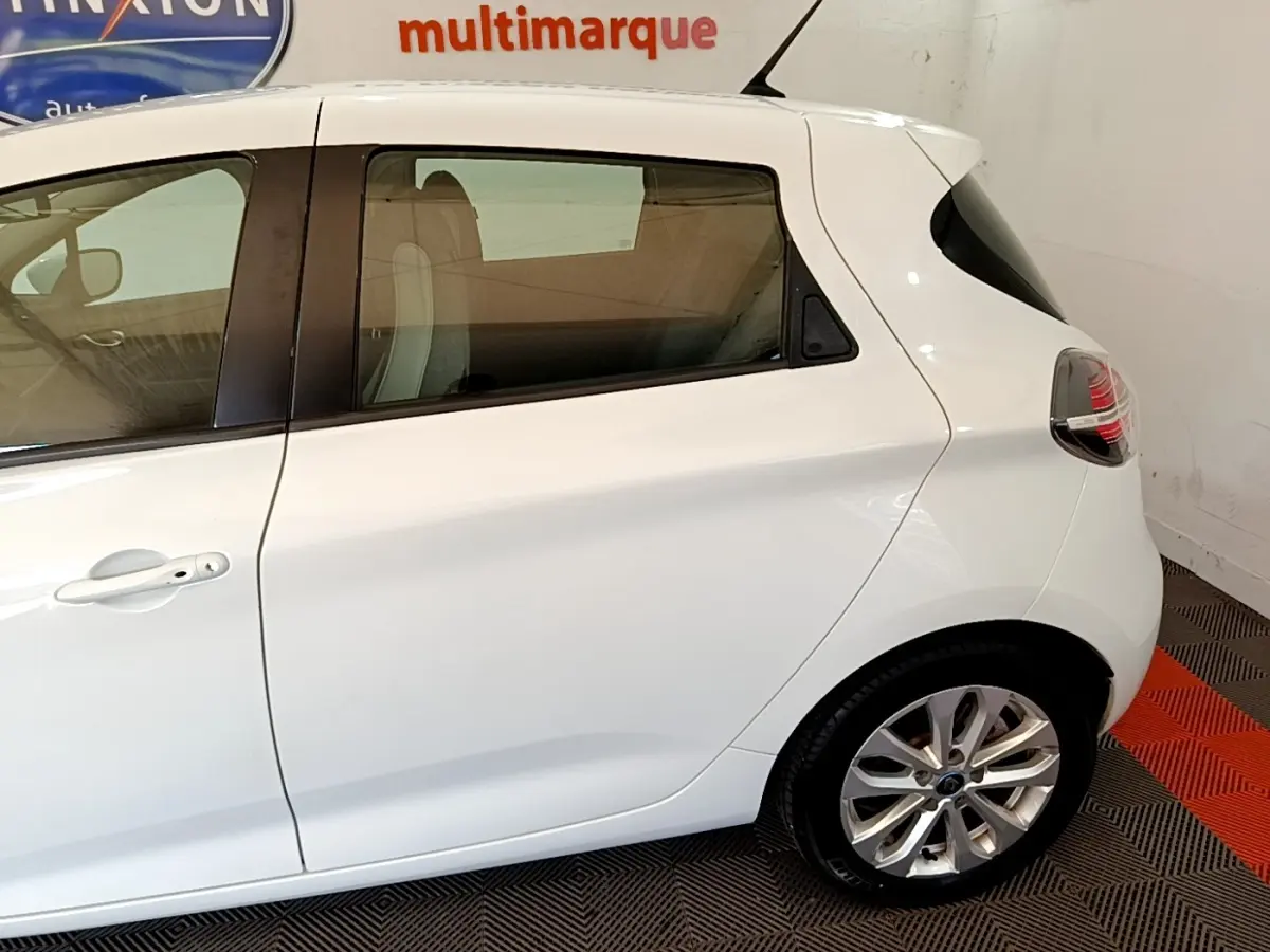Vue latérale droite d'une Renault ZOE blanche 2019 avec jante alliage et vitres teintées arrière.
