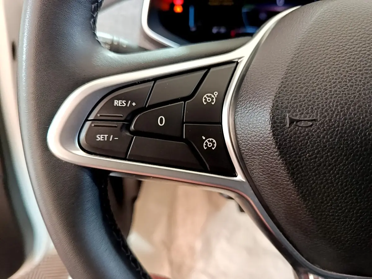 Gros plan sur les commandes de régulateur de vitesse au volant cuir noir de la Renault ZOE blanche.