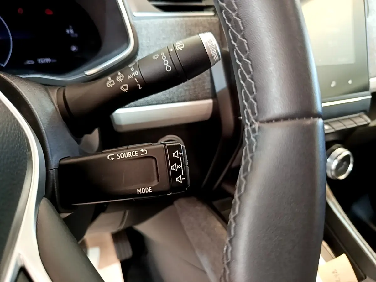 Gros plan sur le volant cuir noir et les commandes au volant du tableau de bord de la Renault ZOE blanche 2019.