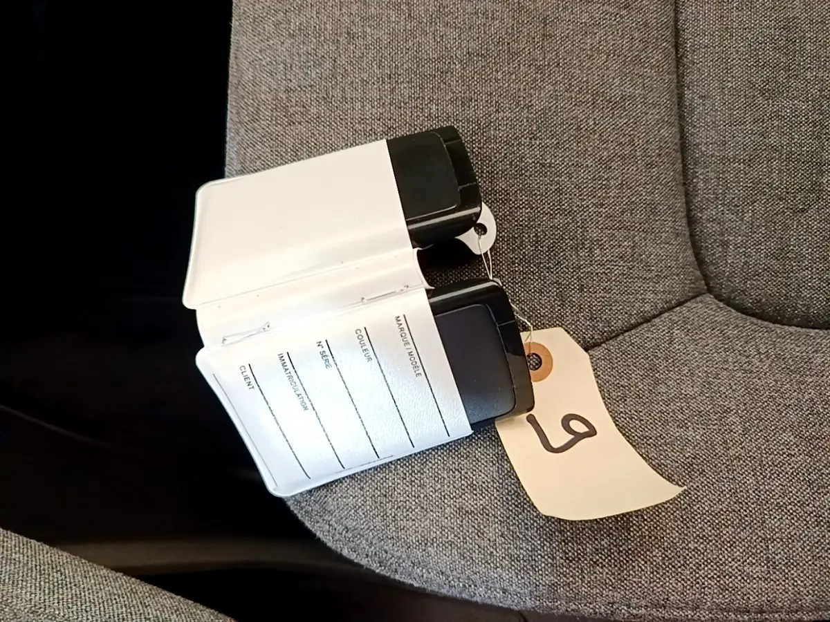 Clé carte Renault ZOE blanche posée sur un siège gris, avec étiquette numérotée attachée.