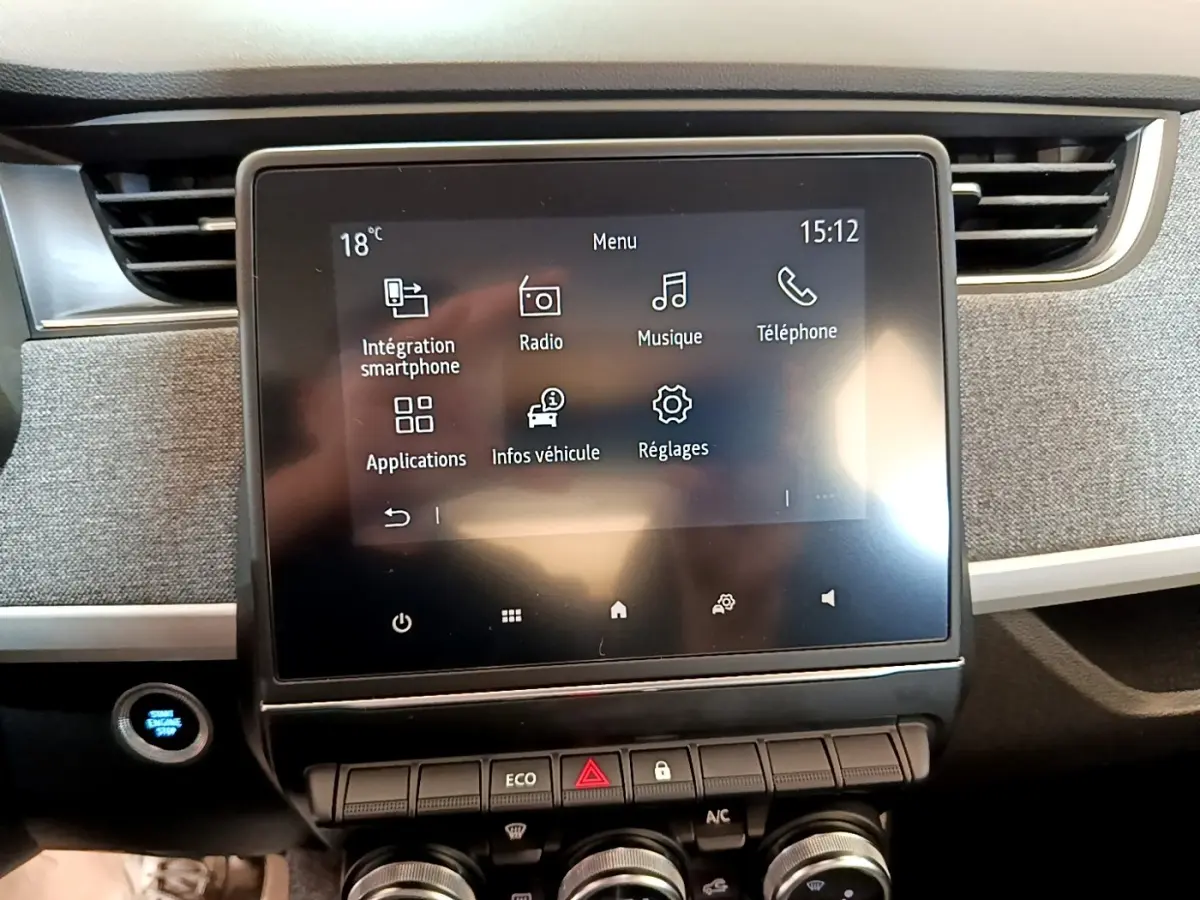 Écran tactile central de la Renault ZOE blanche 2019, affichant le menu multimédia avec commandes sous l'écran.