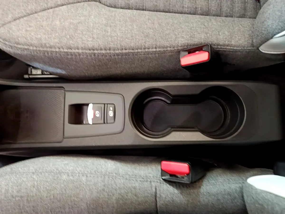Vue plongeante sur la console centrale noire avec porte-gobelets et bouton frein à main électrique de la Renault ZOE blanche.