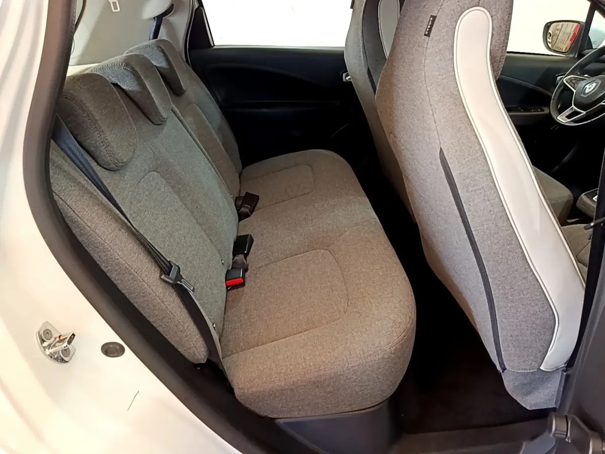 Vue intérieure côté arrière gauche de la Renault ZOE blanche, sièges tissu gris et détails intérieurs modernes.