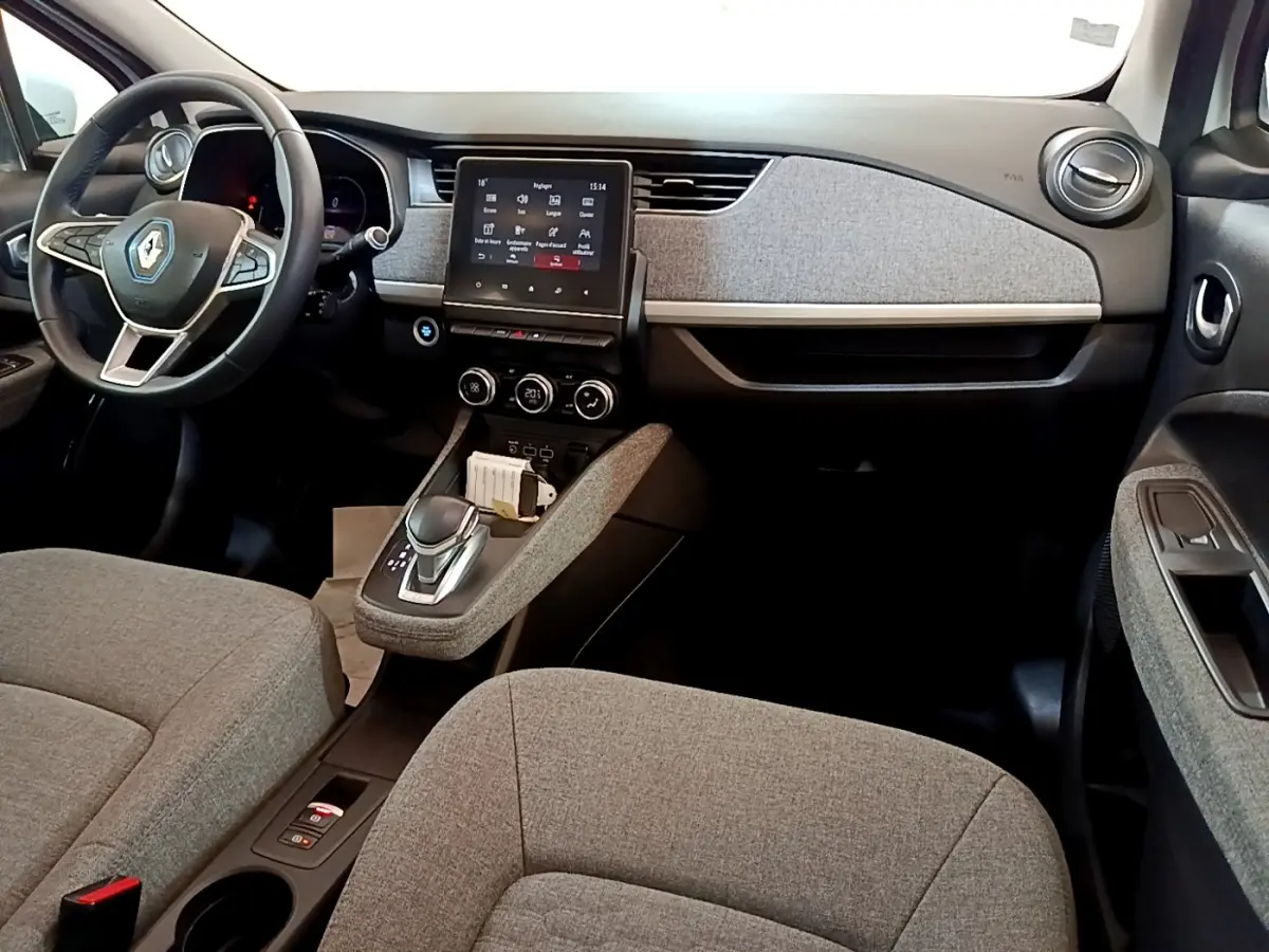 Vue intérieure avant de la Renault ZOE Zen R110, sièges et tableau de bord gris avec écran tactile central.