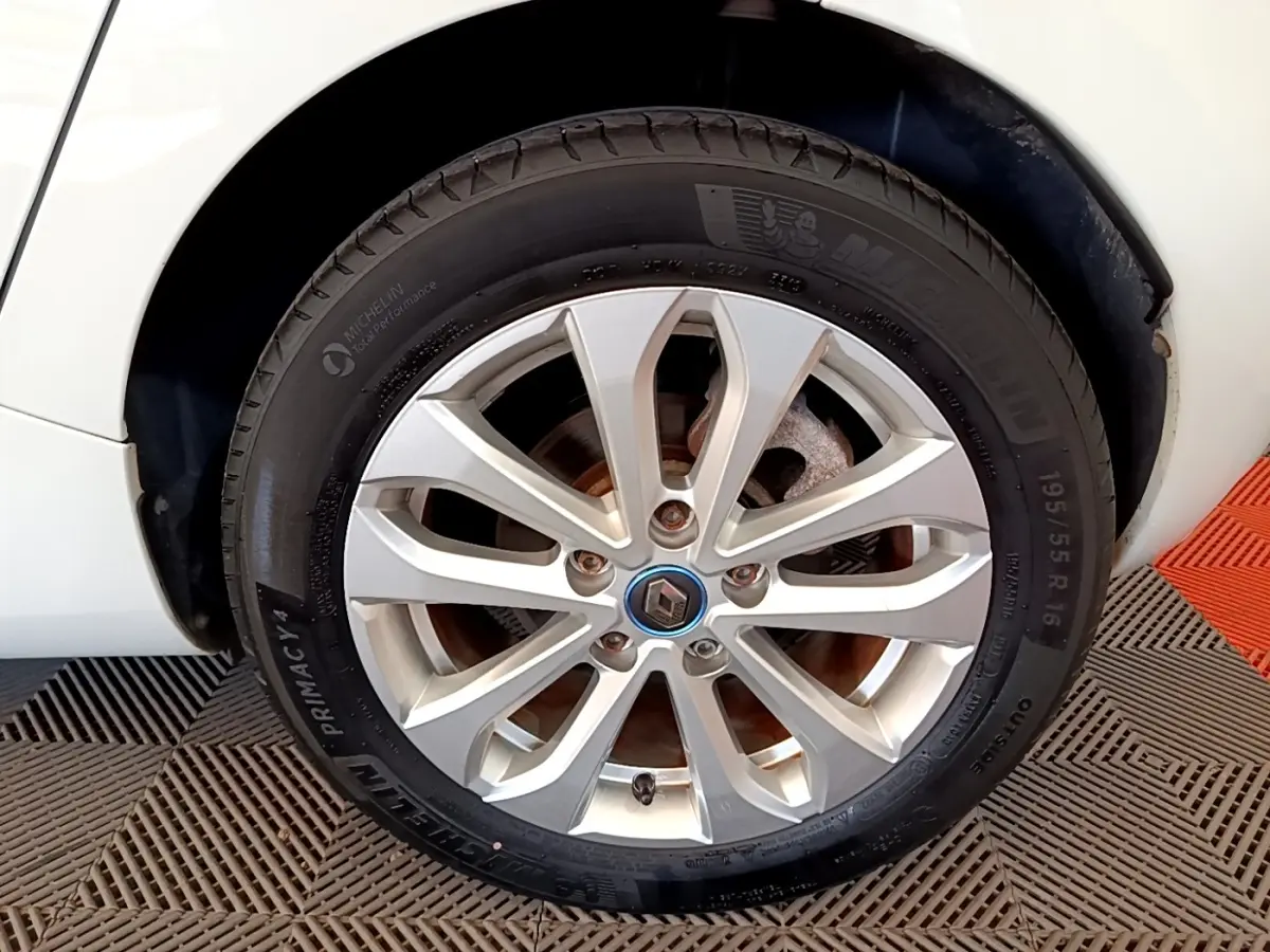 Gros plan sur la roue avant gauche blanche d'une Renault ZOE 2019 avec jante alliage et logo Renault central.