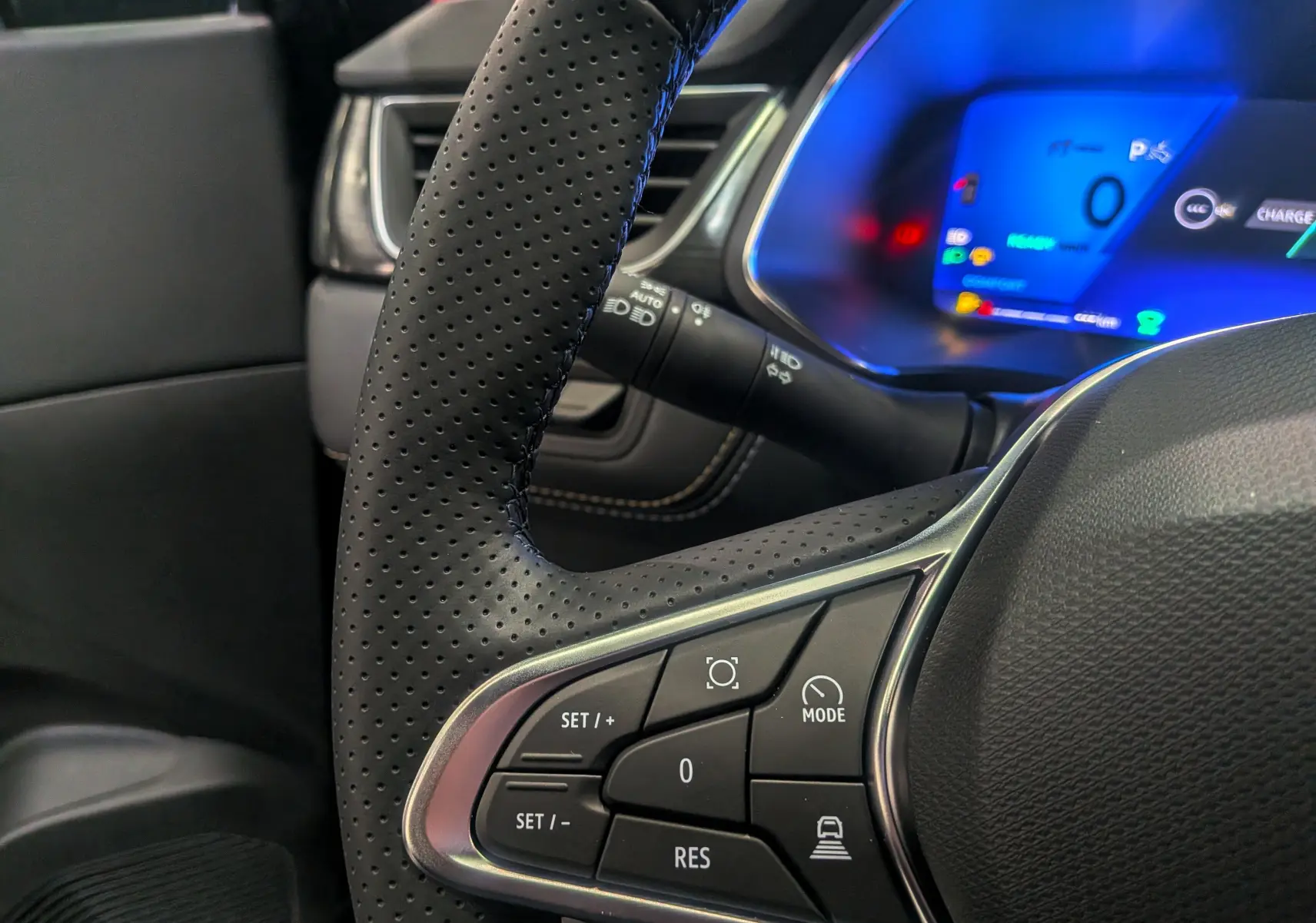 Gros plan sur le volant en cuir perforé et le tableau de bord numérique bleu du Renault Symbioz E-Tech hybride 2026.