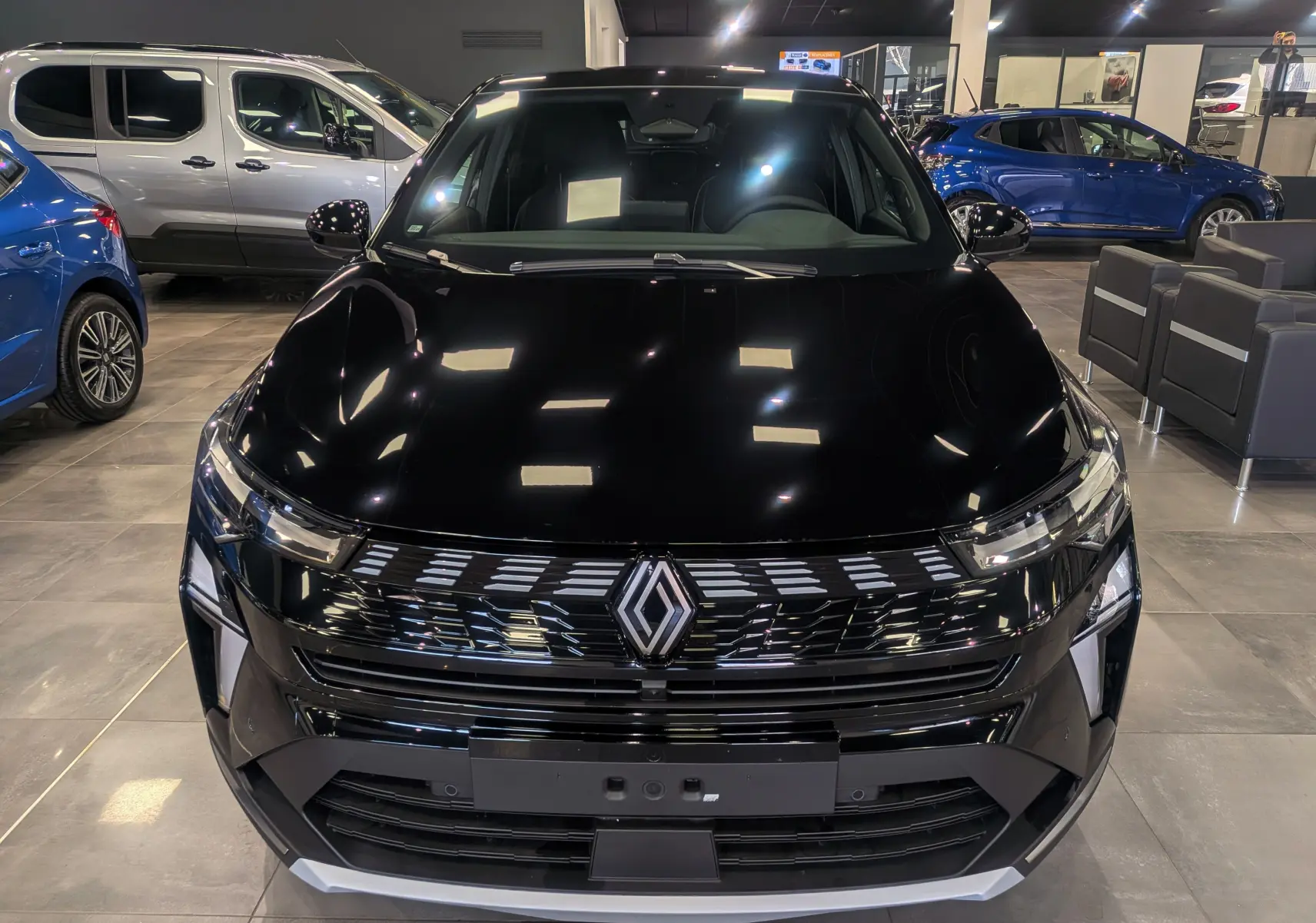 Vue avant d’un Renault SYMBIOZ E-Tech full hybrid noir étoilé, avec calandre moderne et éclairage LED en showroom.